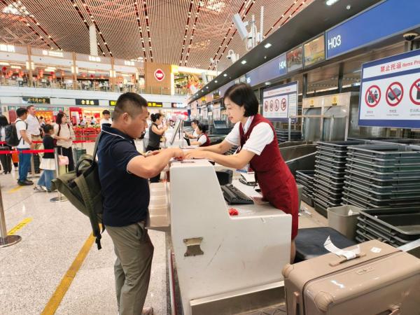 8月12日，搭乘CA723航班的旅客正在北京首都国际机场办理乘机手续。新华社记者王聿昊 摄 